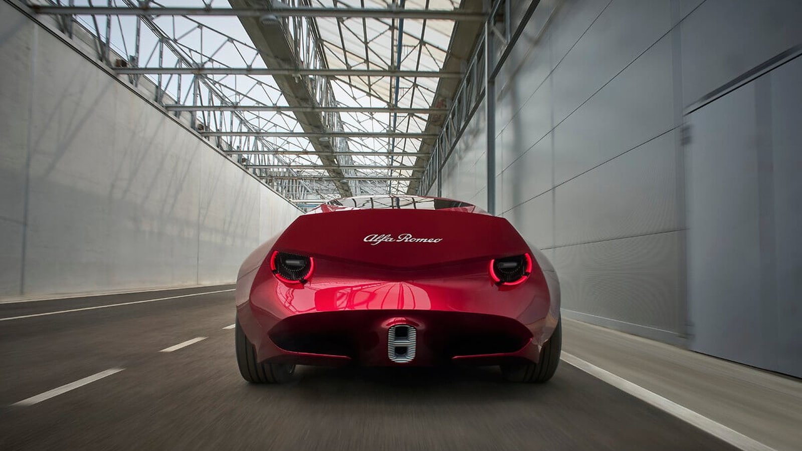 Rear view of the red Alfa Romeo Cuorerosso concept in a tunnel, showing a cut-off tail with two round lights and a shield-shaped rear window
