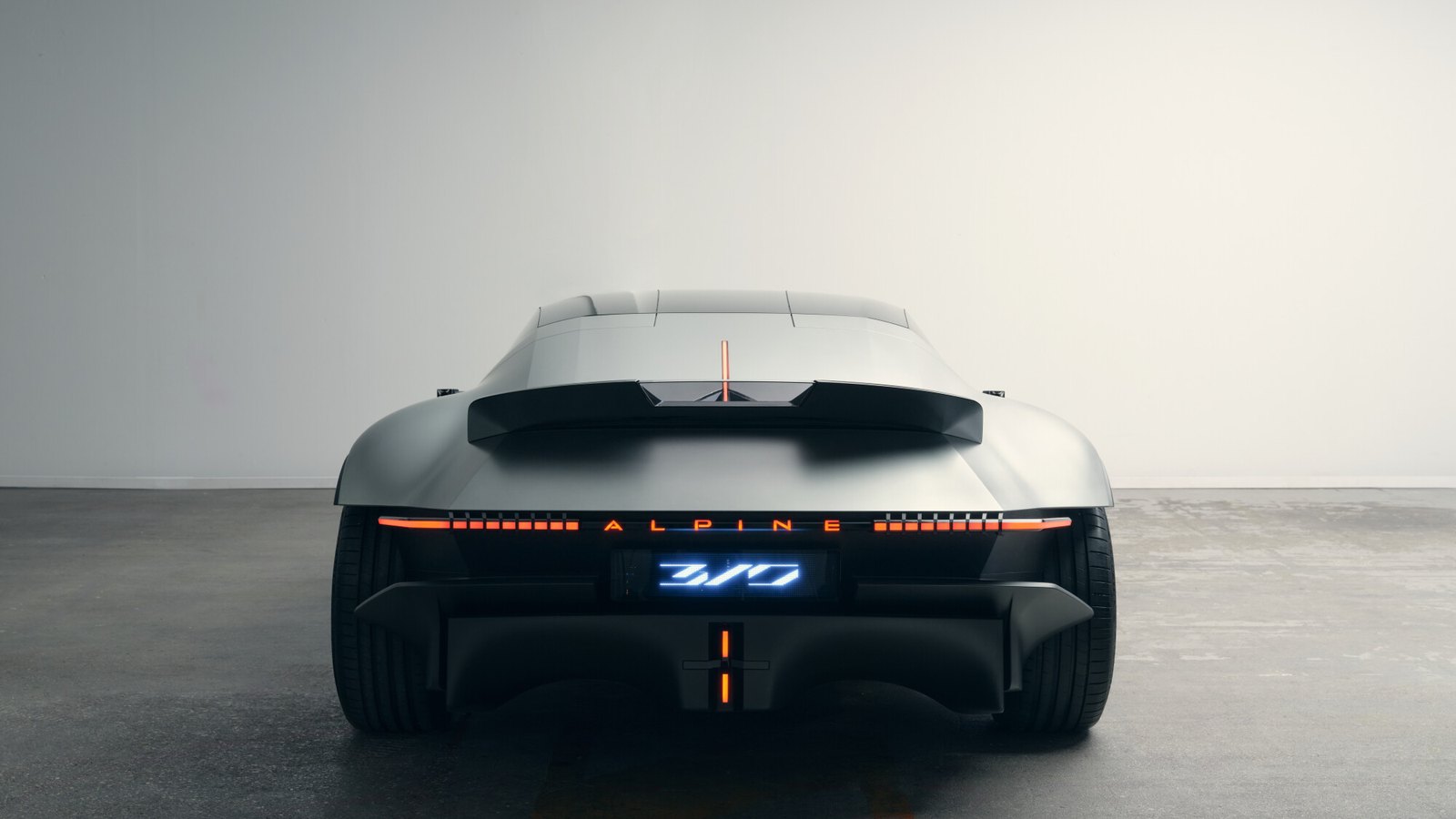 Rear view of the Alpine A310 Vision concept showing a split rear wing, full-width light bar with Alpine lettering and an illuminated 310 badge