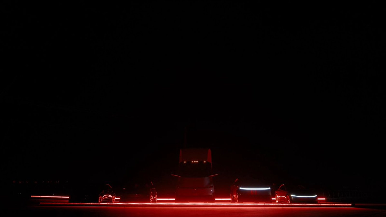 Opening frame of Tesla's "Do a kickflip!" video: a Tesla Semi flanked by Tesla cars lined up in the dark, lit by red light strips, before the Roadster's jump